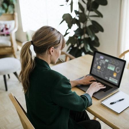 Woman sitting at her dining table with her laptop working remotely